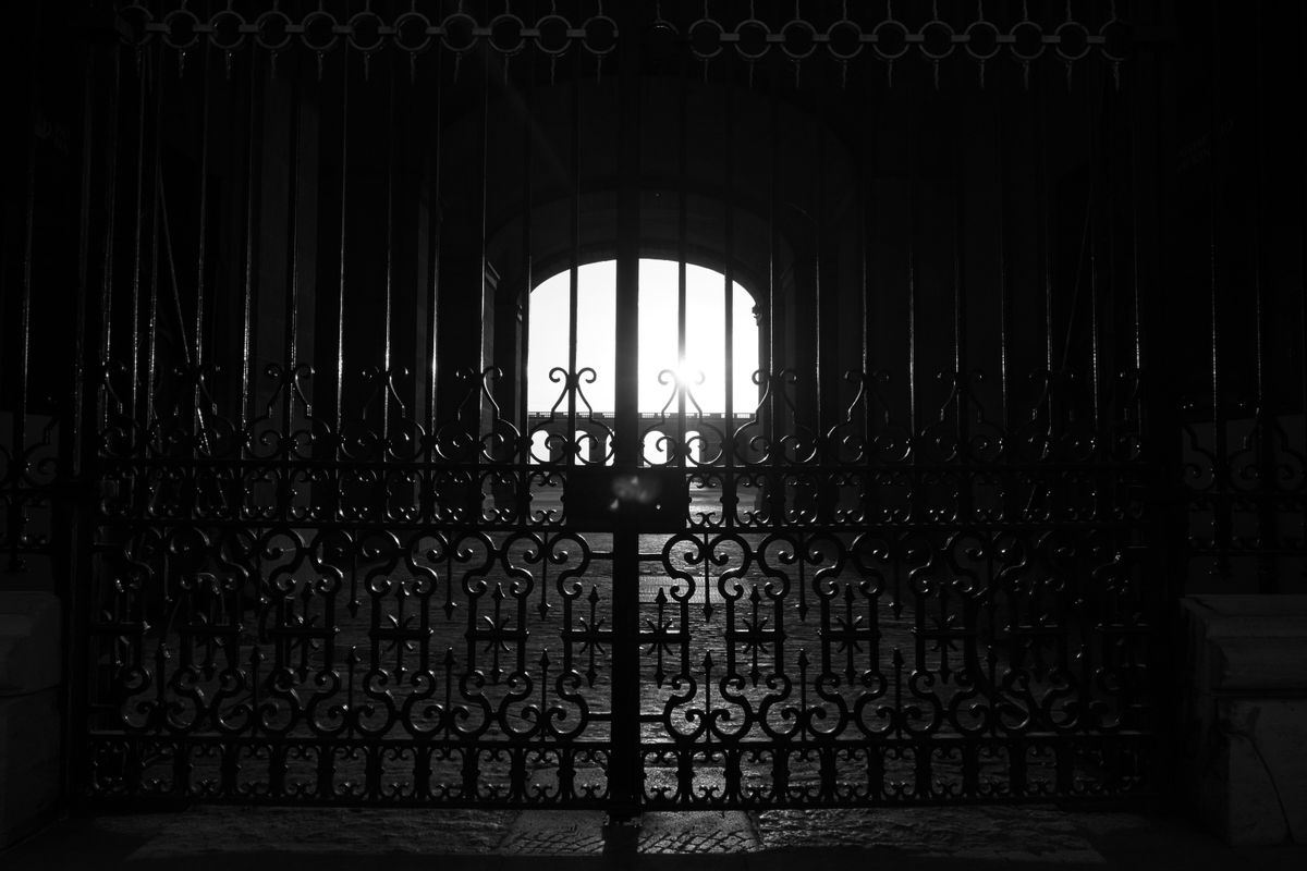 Black and white silhouette of an ornate iron gate with architectural details