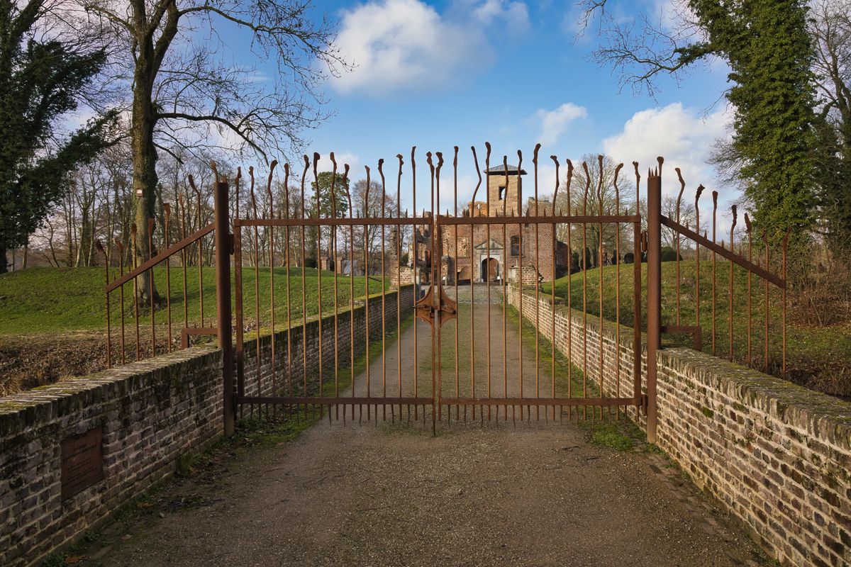 Old stone building behind a rustic iron gate